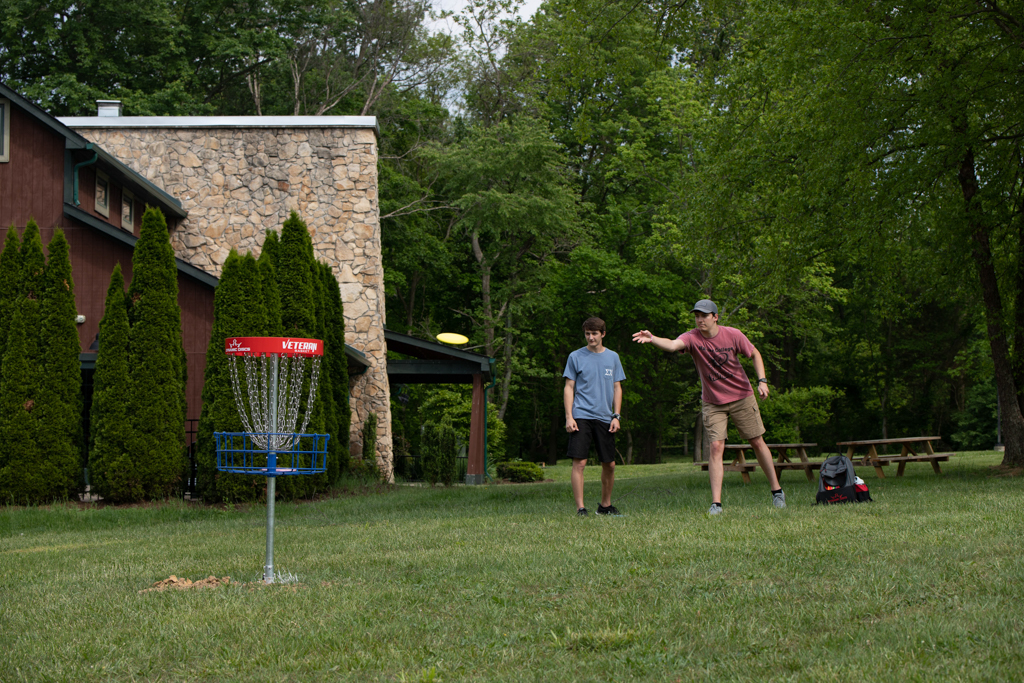 Two student play frisbee golf on the disc golf course