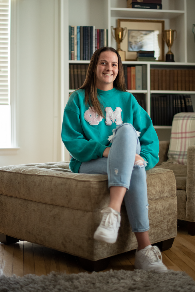 Libby Ward wears Phi Mu sweatshirt in front of a bookcase