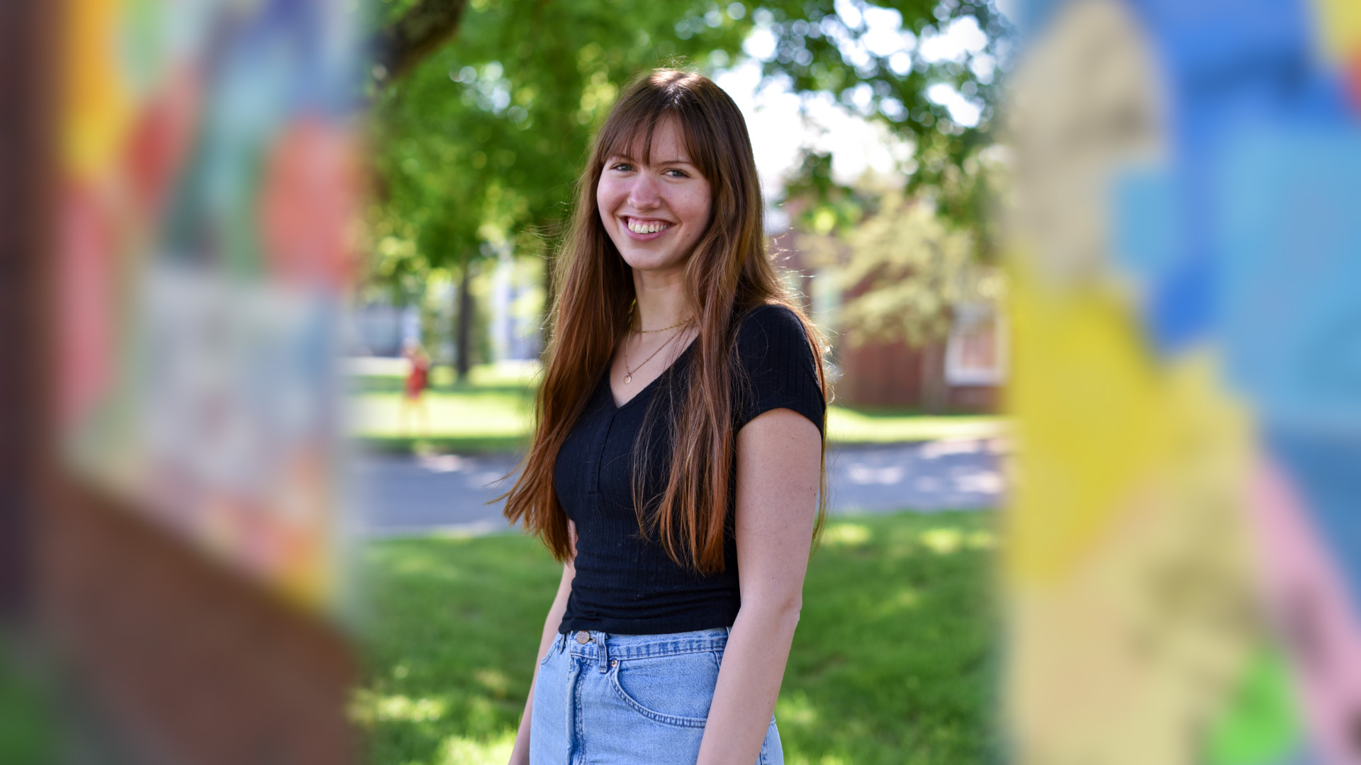 Portrait of Rachel Jordan posing outside superimposed over a blurred photo of her mural