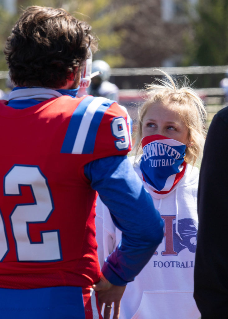 Mya Urba consults with a football player on the sidelines during a game
