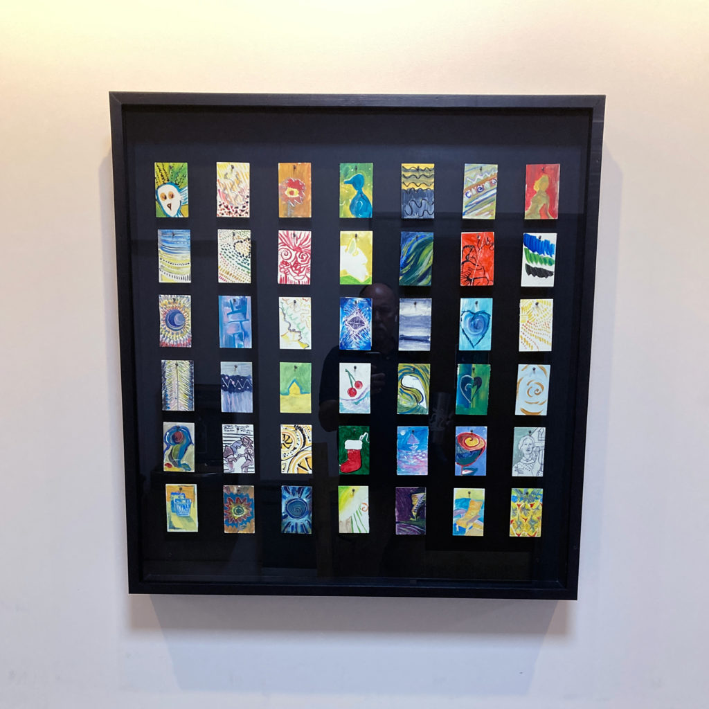a shadow box containing 42 painted tiles