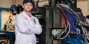 Engineering students support local workforce student wearing protective equipment stands in front of machine