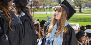 Pondering student in cap and gown